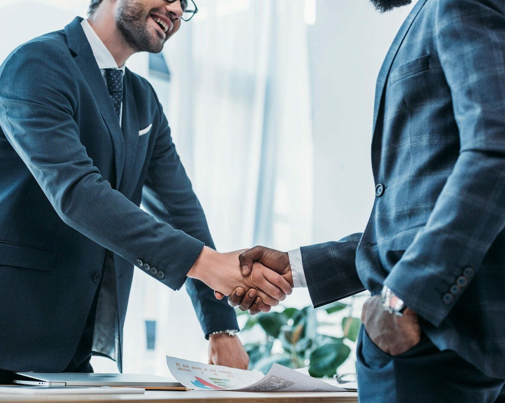 cropped image of smiling multicultural businessmen shaking hands in office